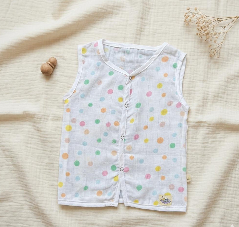 Baby vest with colorful polka dots on a beige fabric background