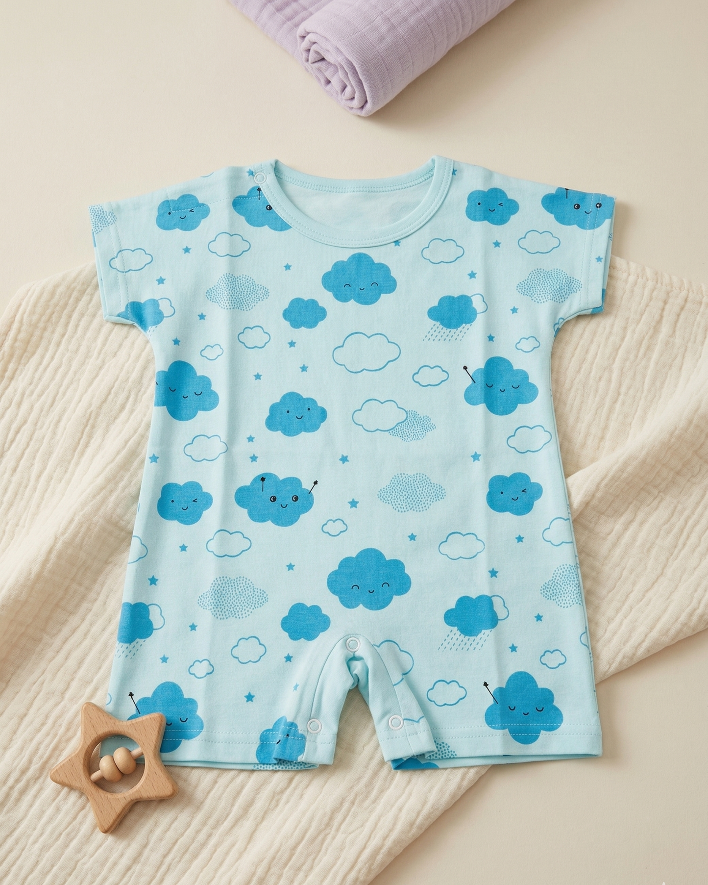Baby romper with blue cloud pattern on a beige surface